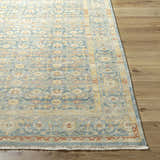 Close-up of the hand-knotted Papakura Area Rug. Oriental design in brick red, gray, mustard, and seafoam on wood floor. Front