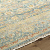 Close-up of the Papakura Area Rug showing its brick red, gray, mustard, and seafoam traditional floral pattern and fringe. Pile