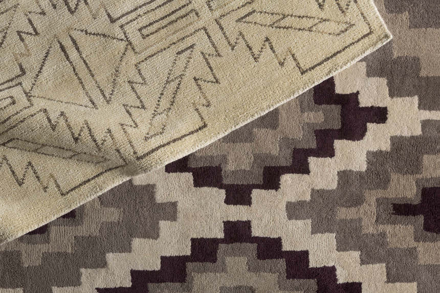 Close-up of the Pawhuska Area Rug: charcoal, peach, and beige geometric patterns. Hand-knotted wool texture. Styleshot