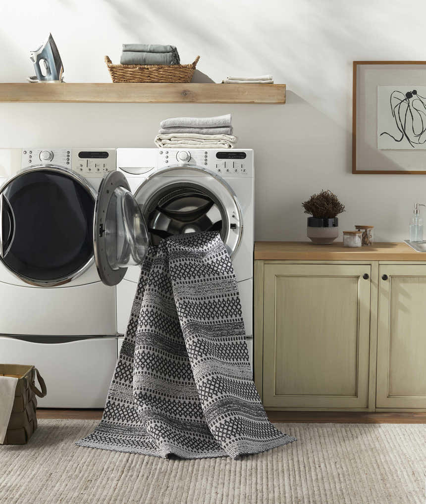 Laundry room scene with Planada Washable Area Rug in black and cream coming out of the washing machine. Washing-Machine