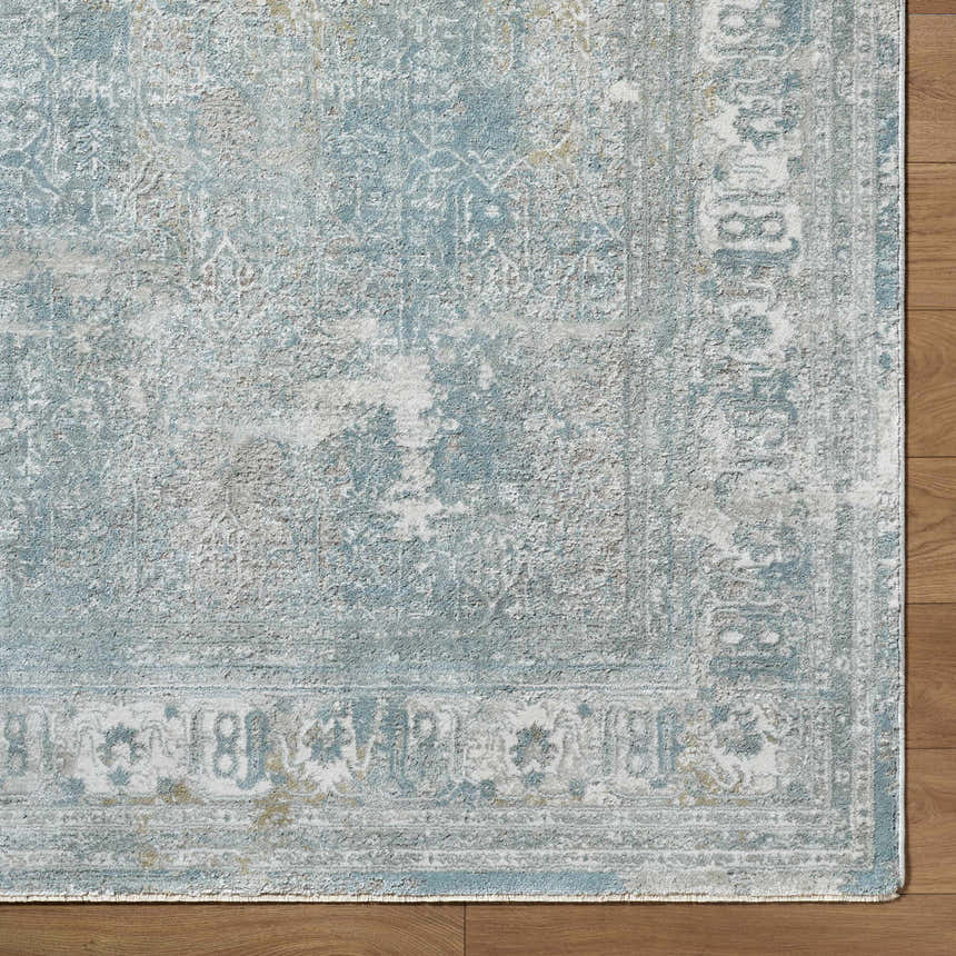 Close-up of the Pryce Blue Gray rug showing the traditional pattern, soft texture, and charcoal, cream, and light gray colors. Corner