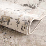 Close-up of the Pewamo Area Rug showing its beige, tan, charcoal, and black contemporary pattern. Fold