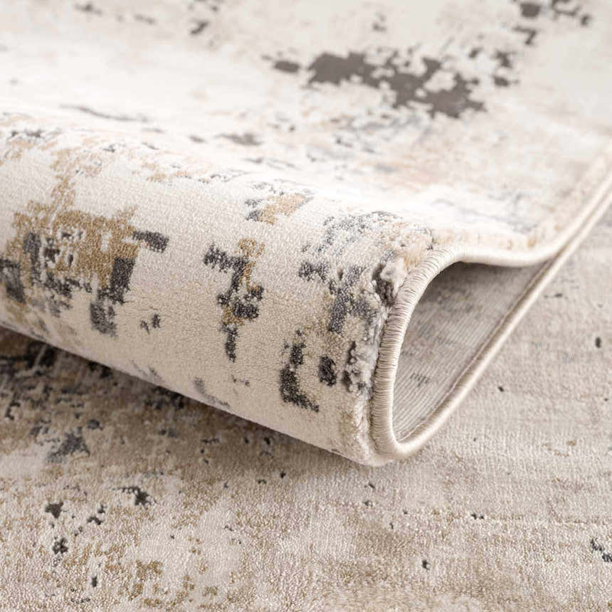 Close-up of the Pewamo Area Rug showing its beige, tan, charcoal, and black contemporary pattern. Fold