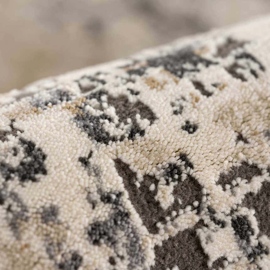 Close up of the Pewamo Area Rug showing its beige, charcoal, and brown contemporary pattern. Fold