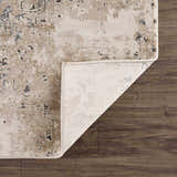 Close-up of the Pewamo Area Rug showing its beige, tan, charcoal, and black contemporary design and texture. Fold