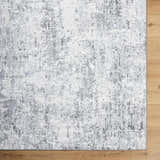 Close-up of the Avital Area Rug, a contemporary rug in black, charcoal, gray, and white, on a wood floor. Corner