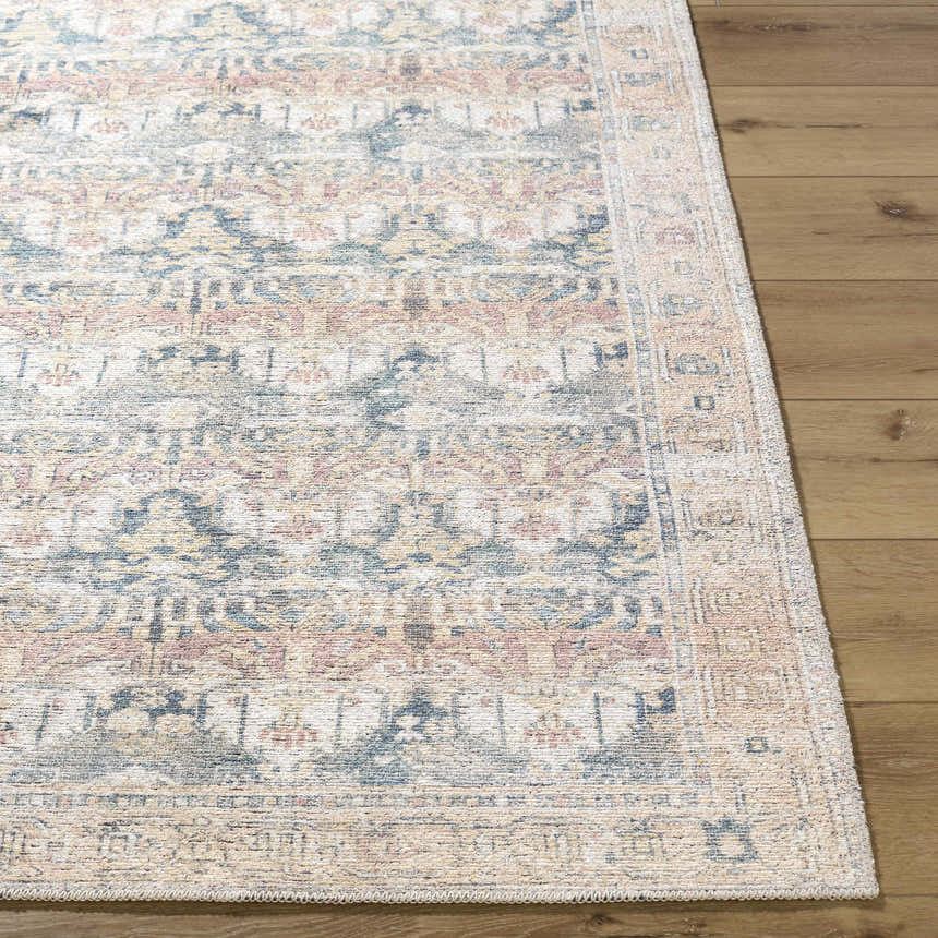 Close-up of the Arushi Washable Area Rug. Cream, blue, and rust traditional pattern on a soft polyester rug. Front