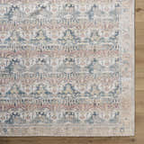 Close-up of the Arushi Washable Area Rug. Farmhouse style rug with cream, green, orange, rust, and tan colors. Corner