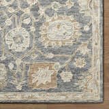 Close up of the hand tufted Auryon Oushak Wool Area Rug. Slate blue rug with off white and tan floral pattern. Corner