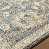 Close up of the Auryon Hand Tufted Oushak Wool Area Rug showing slate blue, off white, and tan floral pattern and wool texture. Texture