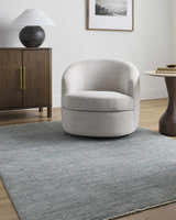 Living room scene with a gray Livabliss x Galey Alix Maria Elena II rug, cream swivel chair, and wood cabinet. Roomscene-Rectangle