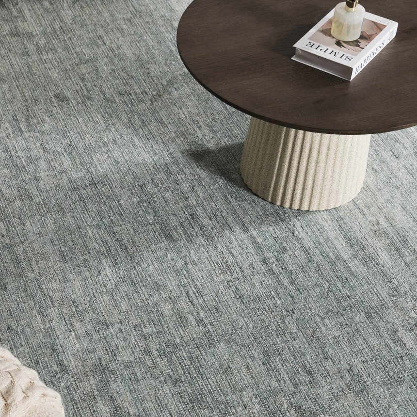 Close up of Livabliss x Galey Alix Maria Elena II rug in medium gray under a round wood coffee table. Roomscene-Rectangle