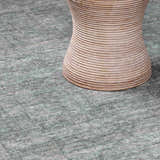 Close-up of Livabliss x Galey Alix Maria Elena II rug in gray with a subtle vintage medallion pattern and a round rattan table. Styleshot
