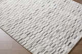 Close-up of the Reece Luxe Rug featuring a contemporary beige, black, and white geometric pattern. Corner