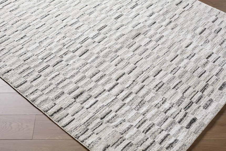 Close-up of the Reece Luxe Rug featuring a contemporary beige, black, and white geometric pattern. Corner
