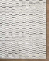 Close-up of the Reece Luxe Rug. Beige, cream, and black horizontal stripes create a contemporary pattern. Corner