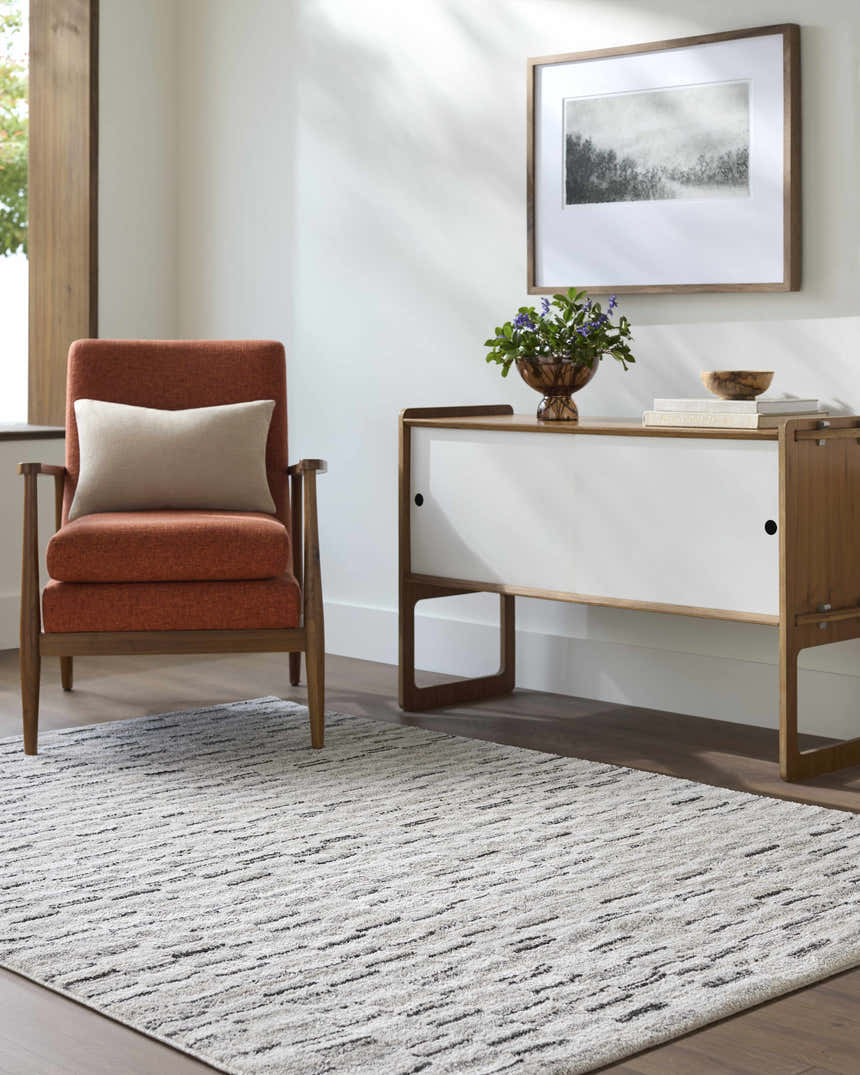 Living room scene with orange chair and white cabinet featuring the beige and black Reece Luxe Rug. Roomscene-Rectangle