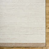 Close up of the hand-tufted Amabel Area Rug. Beige, ivory, and tan wool rug with a subtle stripe detail. Corner