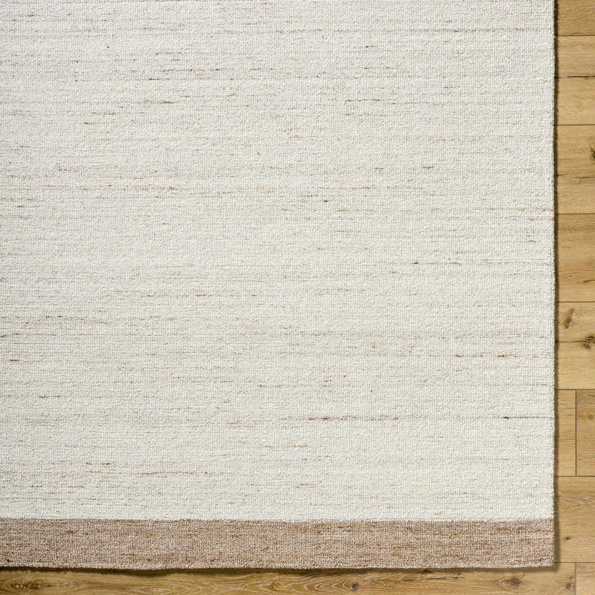 Close up of the hand-tufted Amabel Area Rug. Beige, ivory, and tan wool rug with a subtle stripe detail. Corner
