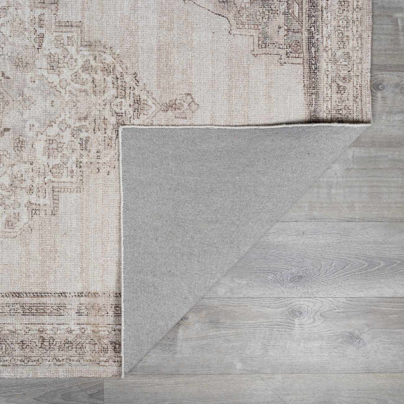 Close up of the beige and dark brown Luciana III Traditional Medallion Area Rug showing pattern and backing. Fold