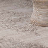 Close up of the beige and dark brown Luciana III Traditional Medallion Area Rug with a neutral rattan table. Styleshot