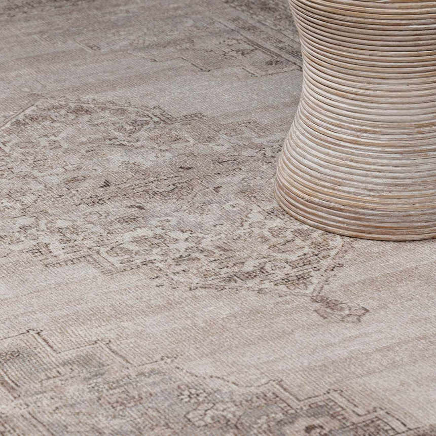 Close up of the beige and dark brown Luciana III Traditional Medallion Area Rug with a neutral rattan table. Styleshot