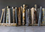 Rolled Sherwood Area Rugs in various colors and patterns against a dark gray wall. Rugs are on clearance. Styleshot
