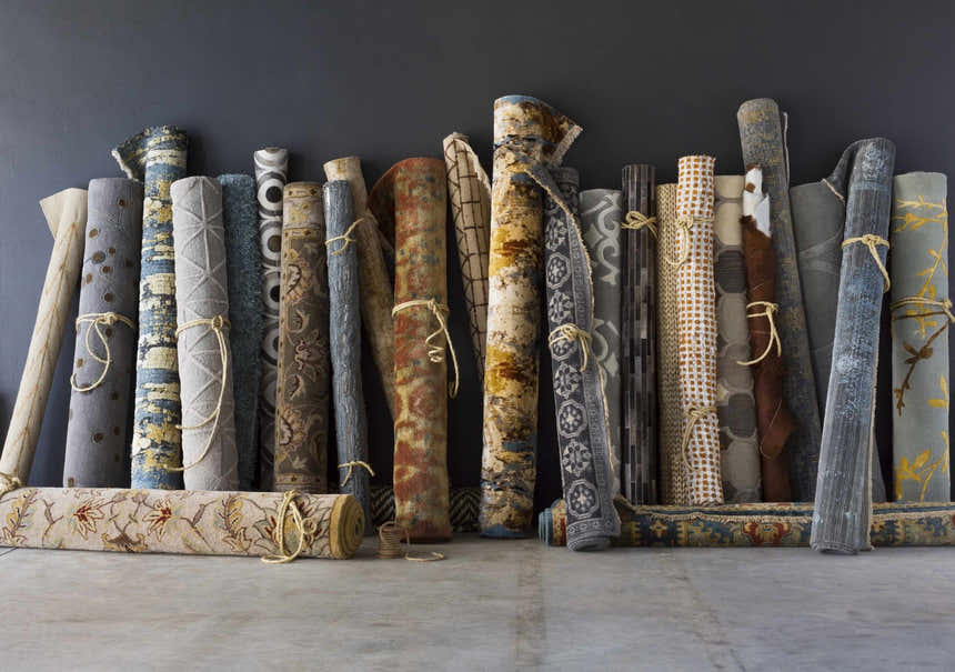 Rolled Sherwood Area Rugs in various colors and patterns, tied with twine. Rugs include Bohemian, Oriental, and Traditional styles. Styleshot