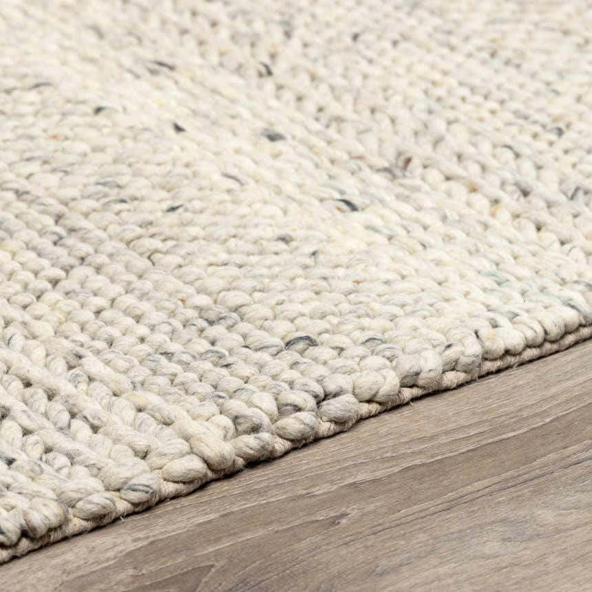 Close-up of the hand woven Salvo Luxury Wool Area Rug. Cream and ivory tones with subtle black flecks. Thick, textured wool. Pile