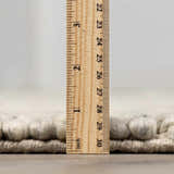 Close-up of the Salvo Luxury Rug showing its pile height with a ruler. Cream and wool texture. Pile