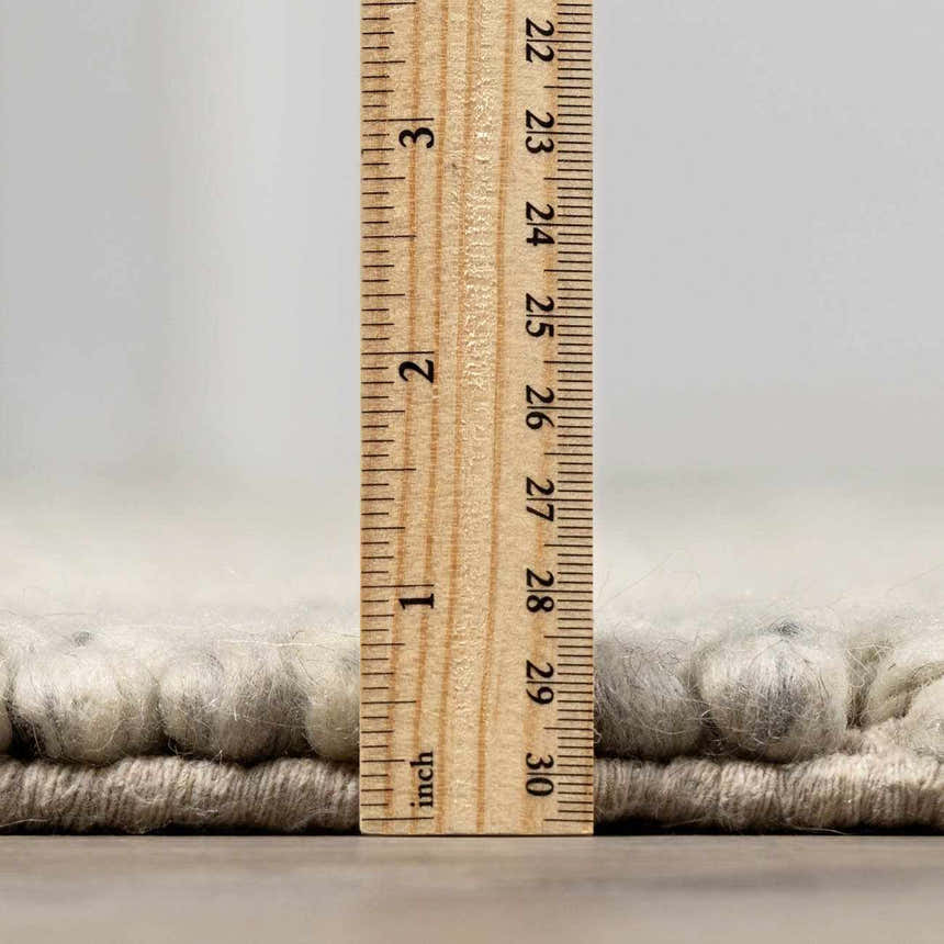 Close-up of the Salvo Luxury Rug showing its pile height with a ruler. Cream and wool texture. Pile