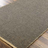 Close-up of the Kimi Machine Woven Becki Owens x LIVABLISS rug. Black and light brown jute with a textured, grid-like design. Corner