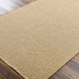 Close-up of the light brown Kimi Machine Woven Becki Owens x LIVABLISS area rug showing jute texture and woven pattern. Corner