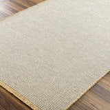 Close-up of the Kimi Becki Owens x LIVABLISS rug. Gray and light brown jute texture on wood floor. Corner