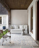 Covered patio with white sofa and Ren Outdoor Becki Owens x LIVABLISS BOMG-2300 Washable Area Rug in charcoal, gray, navy, and taupe. Roomscene-Rectangle