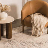 Living room scene with a Becki Owens x LIVABLISS Lila rug, tan leather chair, and round side table with vase. styleshot