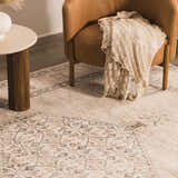 Close-up of Becki Owens x LIVABLISS Lila rug with off-white, brown, and red traditional pattern under a chair and side table. Styleshot