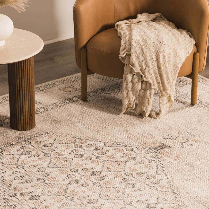 Close-up of Becki Owens x LIVABLISS Lila rug with off-white, brown, and red traditional pattern under a chair and side table. Styleshot