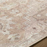 Close up of the Esau Area Rug, a machine woven rug in beige, blush, and ivory with a traditional pattern. Texture