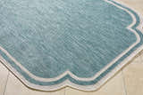 Close-up of the Arnola Light Blue Outdoor Rug showing aqua tones and cream border on beige tile. Corner