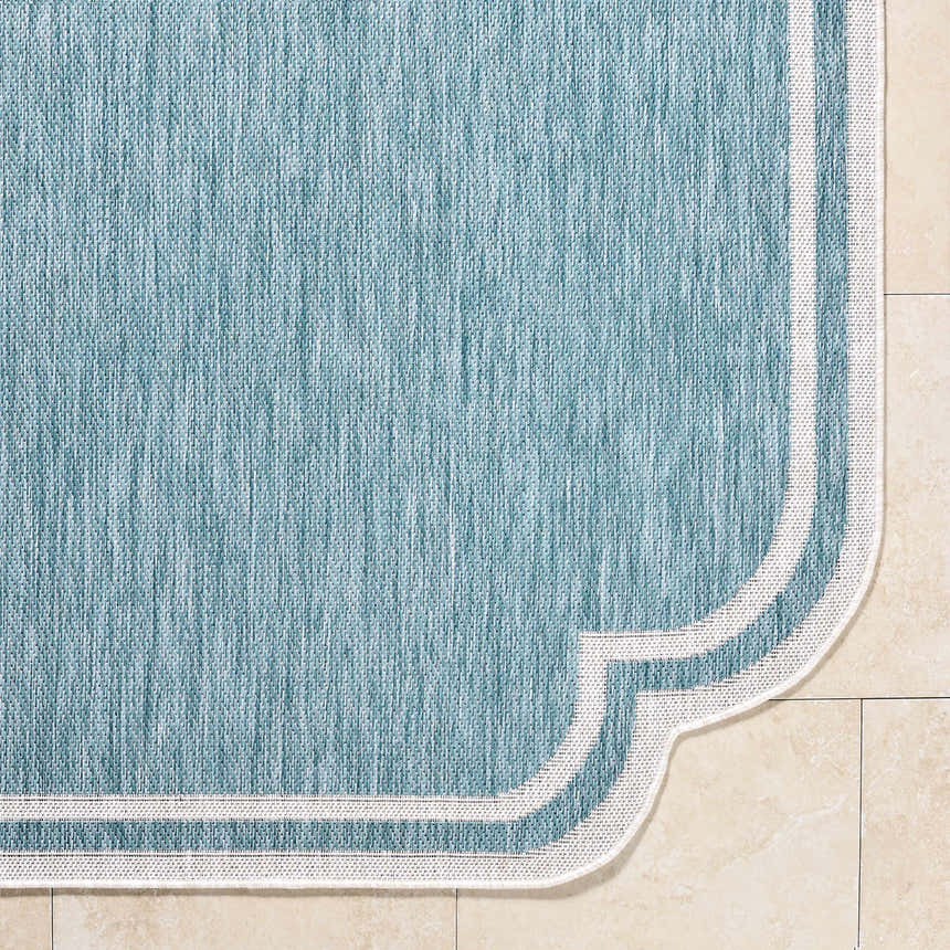 Close-up of Arnola Light Blue Outdoor Rug showing aqua color, woven texture, and cream border detail. Corner
