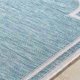 Close up of Arnola Light Blue Outdoor Rug showing woven texture and cream stripes. Texture