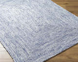 Close-up of the hand-woven Kenyi Navy Area Rug showing its navy and white color and textured, contemporary design. Corner