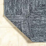 Close-up of the hand-woven Kenyi Black Area Rug showing black and white recycled PET yarn texture and corner detail. Fold