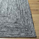 Close-up of the hand woven Kenyi Black Area Rug showing its texture and black and white color on a wood floor. Front