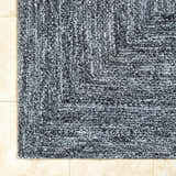Close-up of the hand-woven Kenyi Black Area Rug showing its black and white yarn and textured, contemporary design. Corner