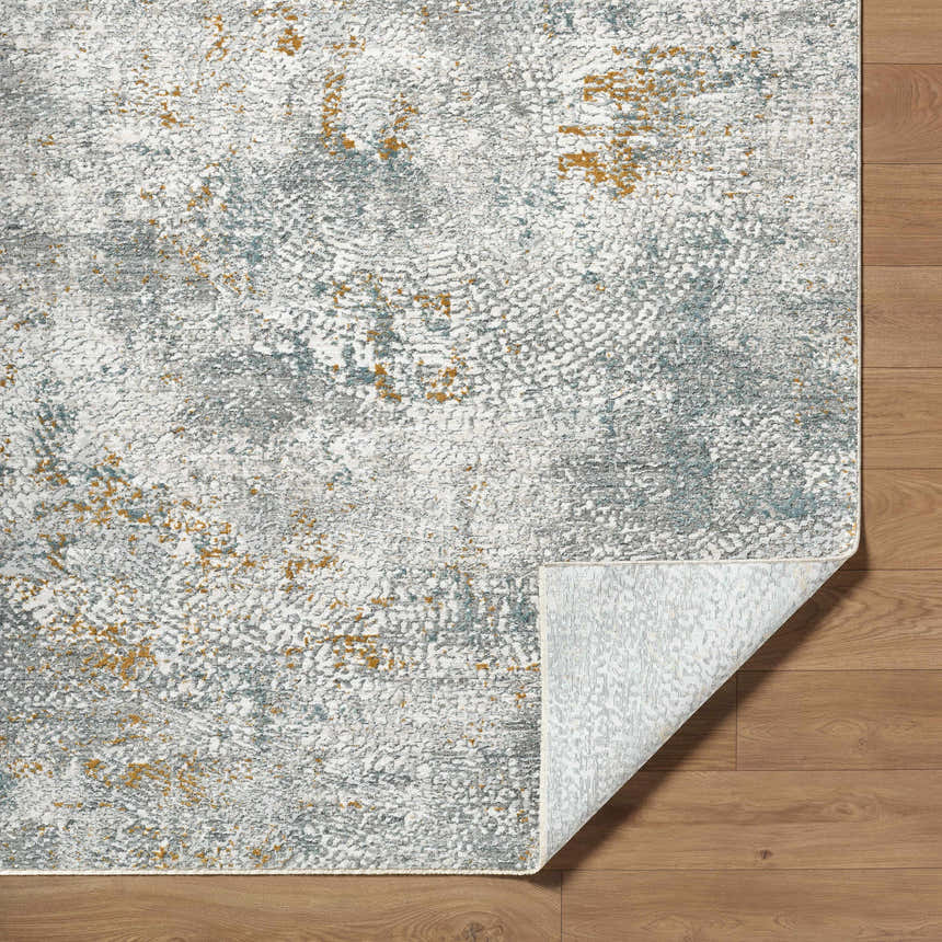 Close-up of Fleur Textured Rug with Fringes. Abstract pattern in gray, light gray, blue and nutmeg. Machine woven polyester rug. Fold