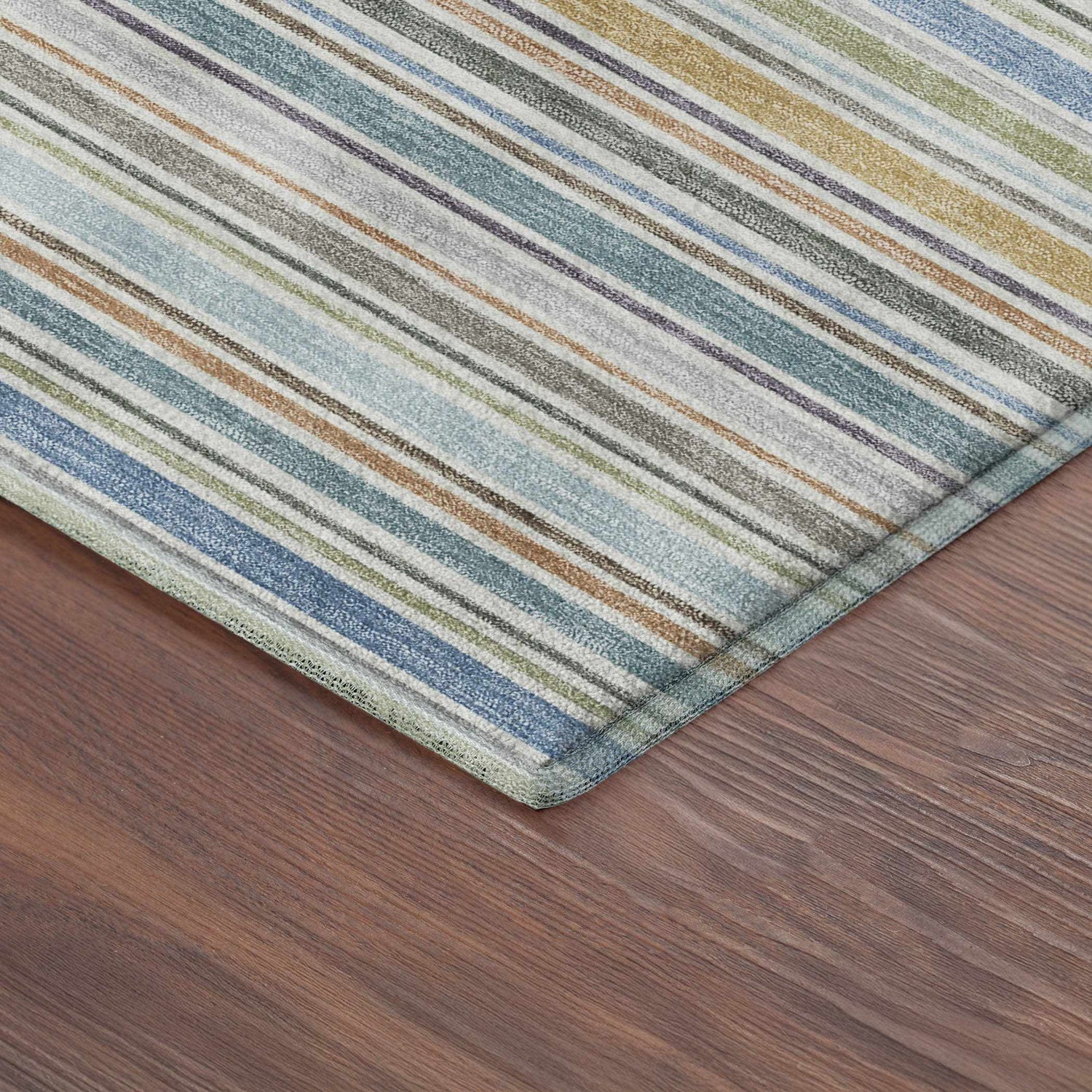 Close up of Dalyn Luxury Soft Essentials Seaside rug with blue, green, and brown stripes on wood floor.