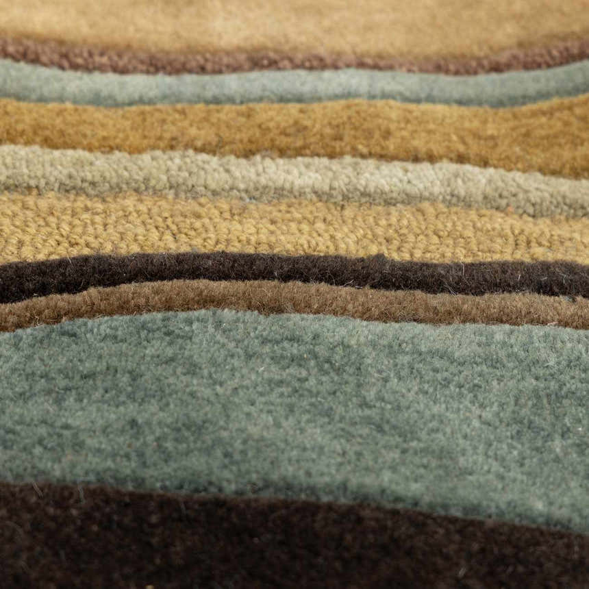 Close-up of the Seminole Area Rug showing the hand-tufted texture and striped pattern in beige, brown, teal, and mustard tones. Texture