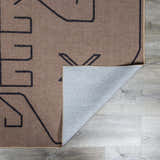Close-up of the Hamid Washable Jutely Rug in camel with a dark brown geometric pattern and recycled fabric backing. Fold